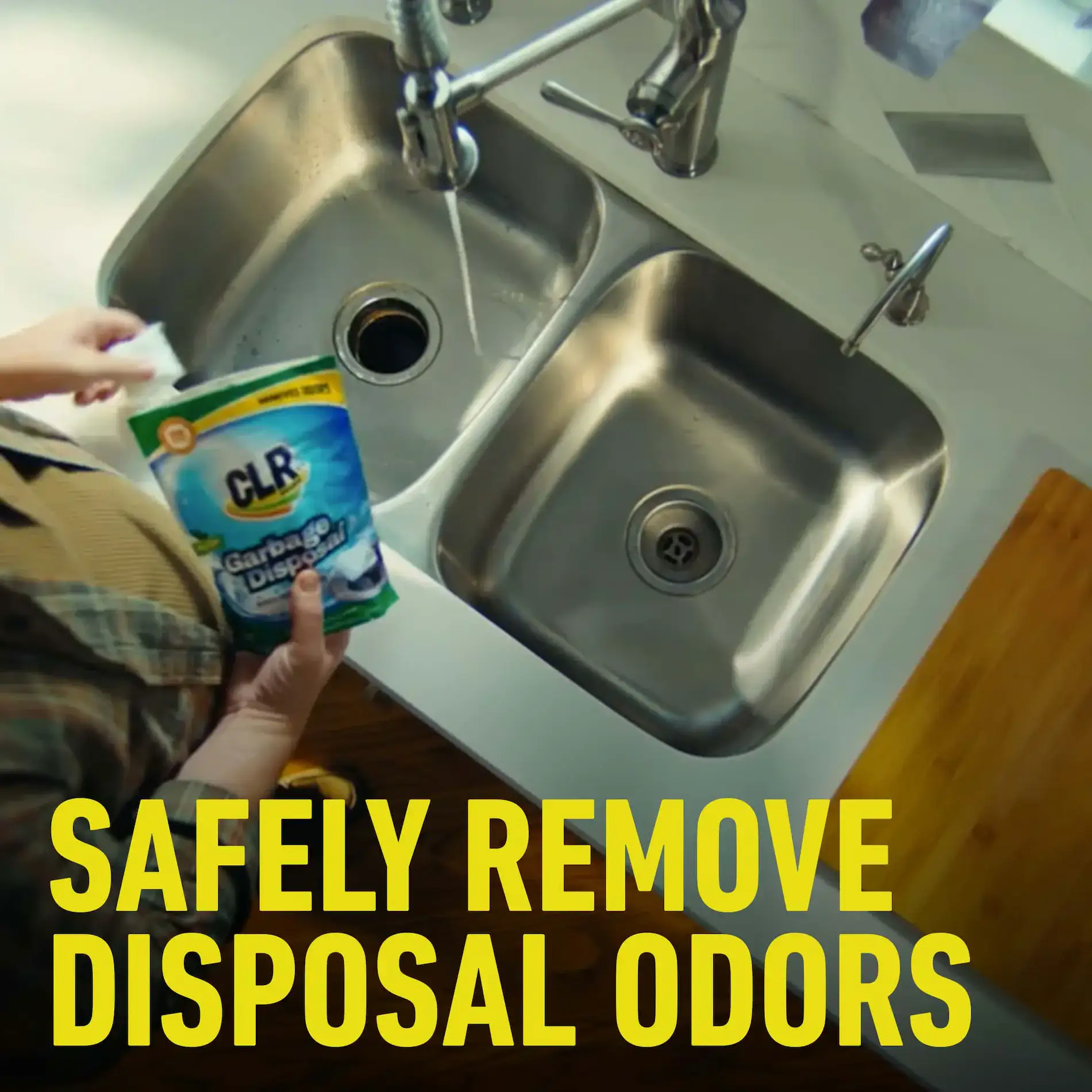 Person holds CLR Garbage Disposal Cleaner pouch over kitchen sink, bold text: Safely Remove Disposal Odors.