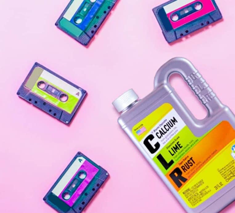 CLR cleaner bottle and four colorful cassette tapes on a pink surface, tapes arranged diagonally.