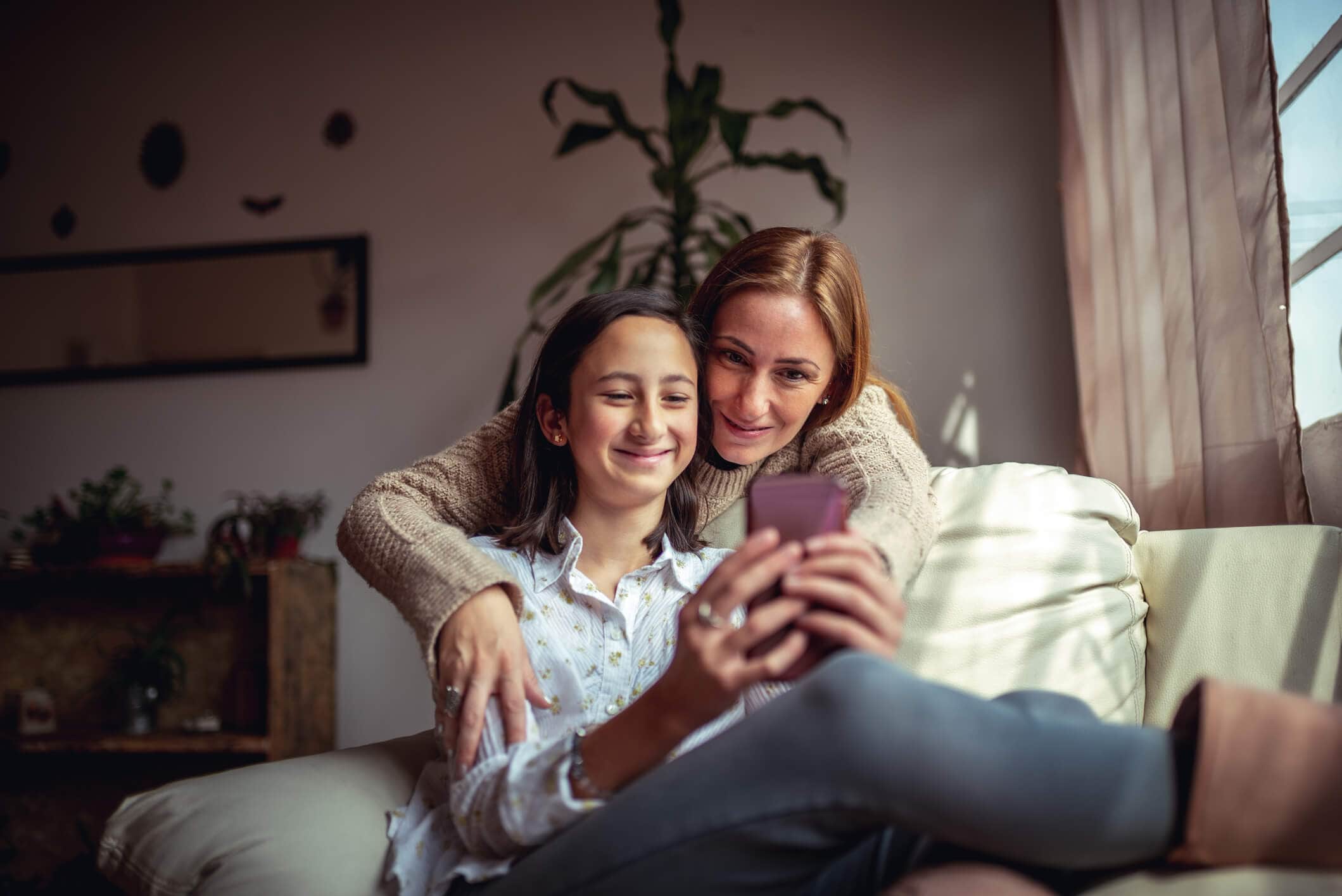 mother and daughter smiling, looking at phone