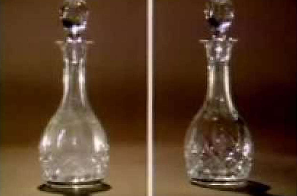 Two glass decanters with stoppers sit side by side on a plain background.